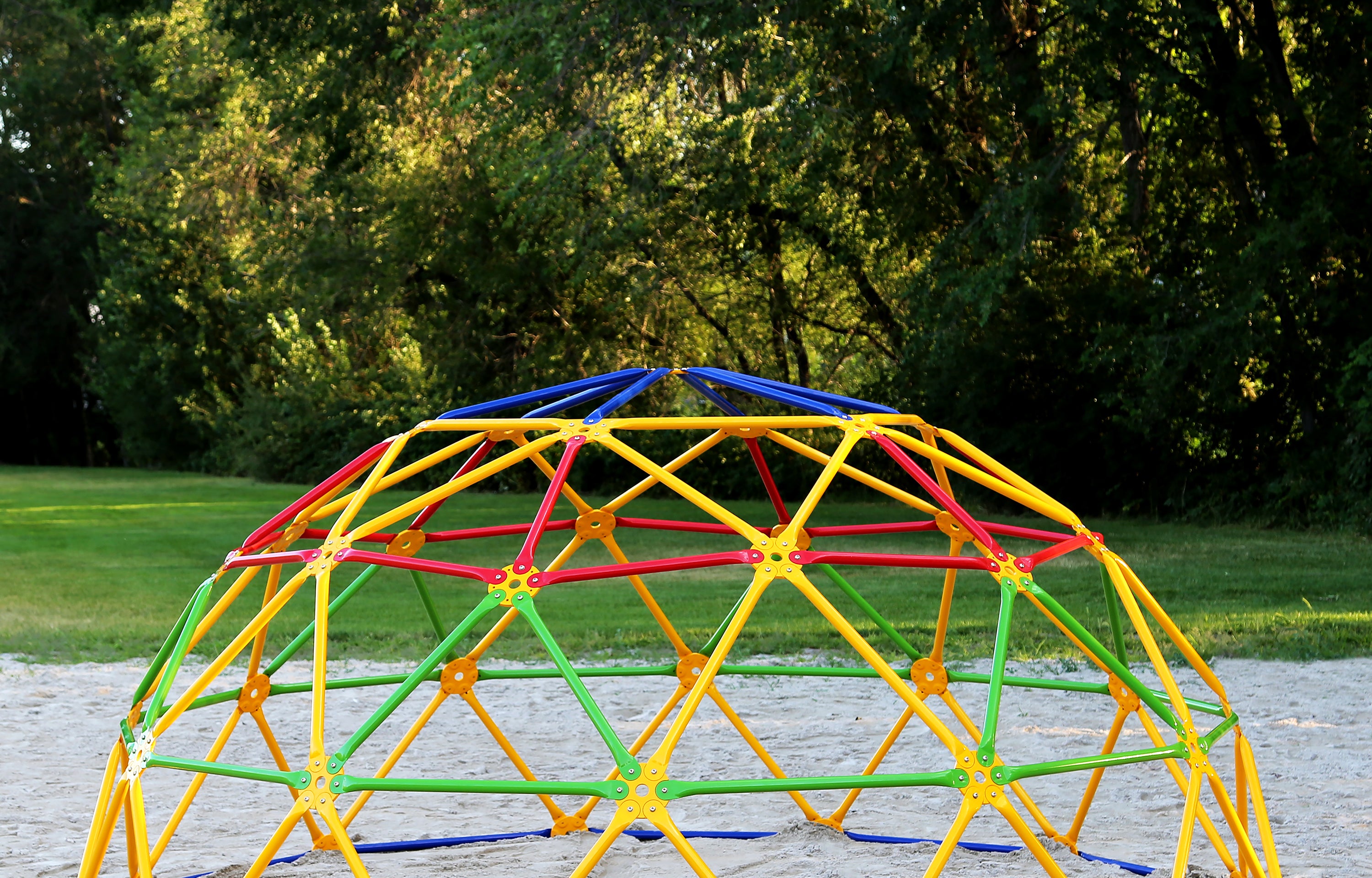 A young girl swinging on the inside of the colorful GeoDome.