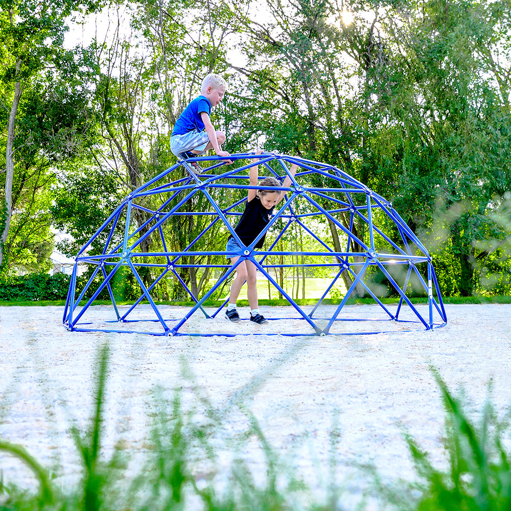 A little boy sits on the top of the Geo Dome while a little girl hangs onto the inside of the Geo Dome. 