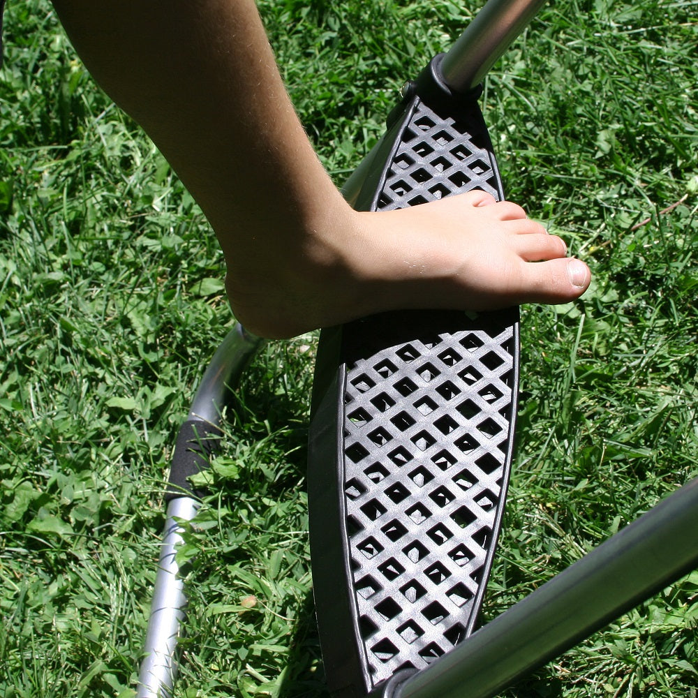 Child's foot stepping onto the plastic ladder step with grass in the background. 