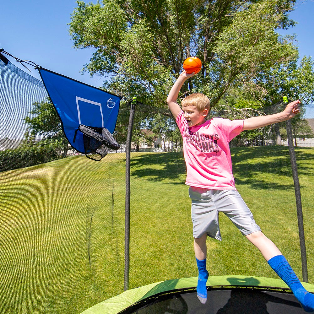 Boy dunking foam basketball into basketball hoop.