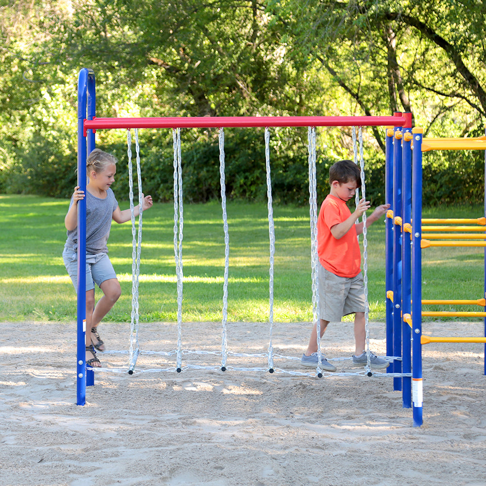 A young boy and girl are walking across the suspended steps on the Hanging Bridge playset.