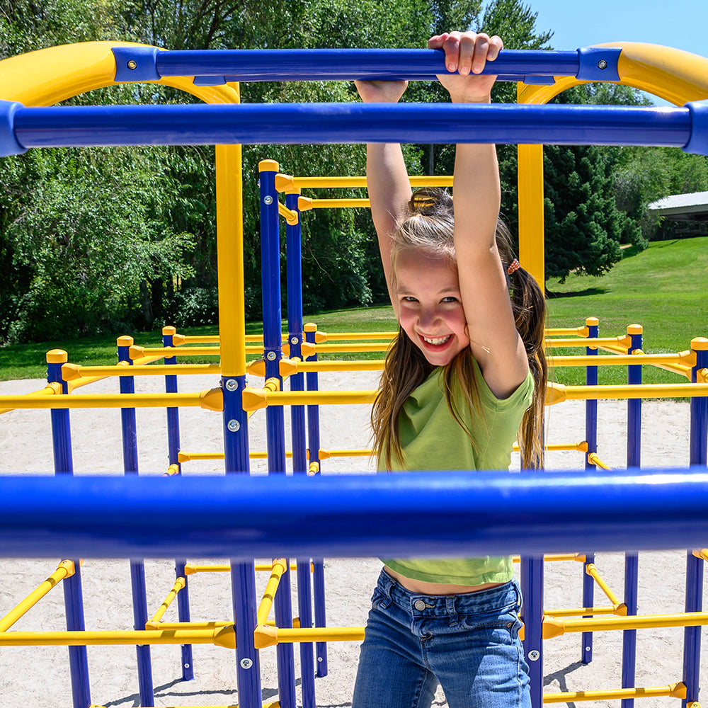 Happy young girl is hanging from the underside of the Arched Ladder.