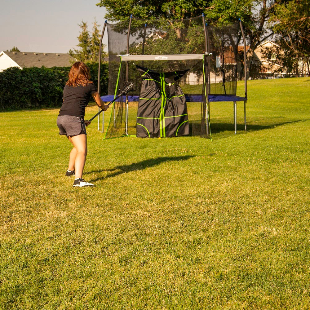 Girl throwing lacrosse ball at the mat's target zones. 