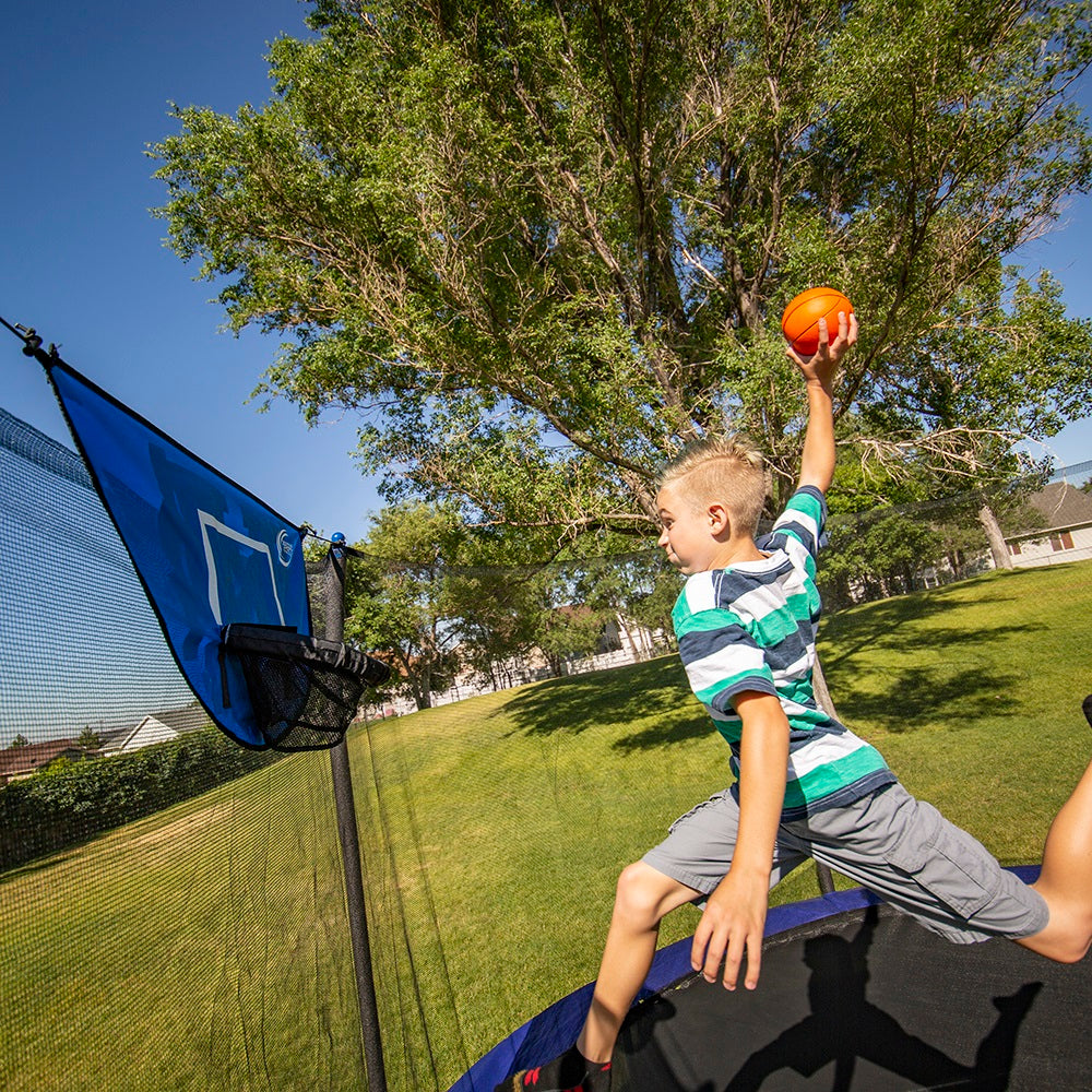 The young boy jumps high in order to dunk the basketball. 