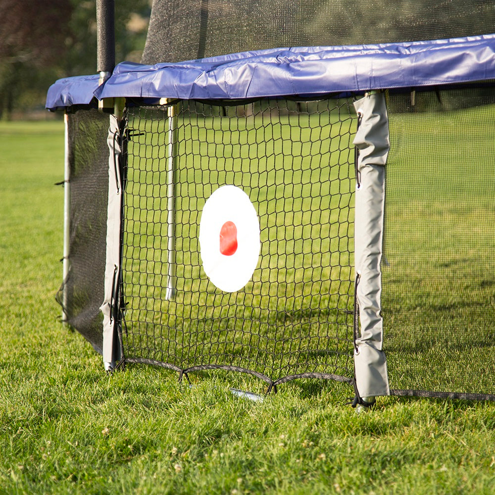 Trampoline with Kickback Game net attached sits in the grass outside.   