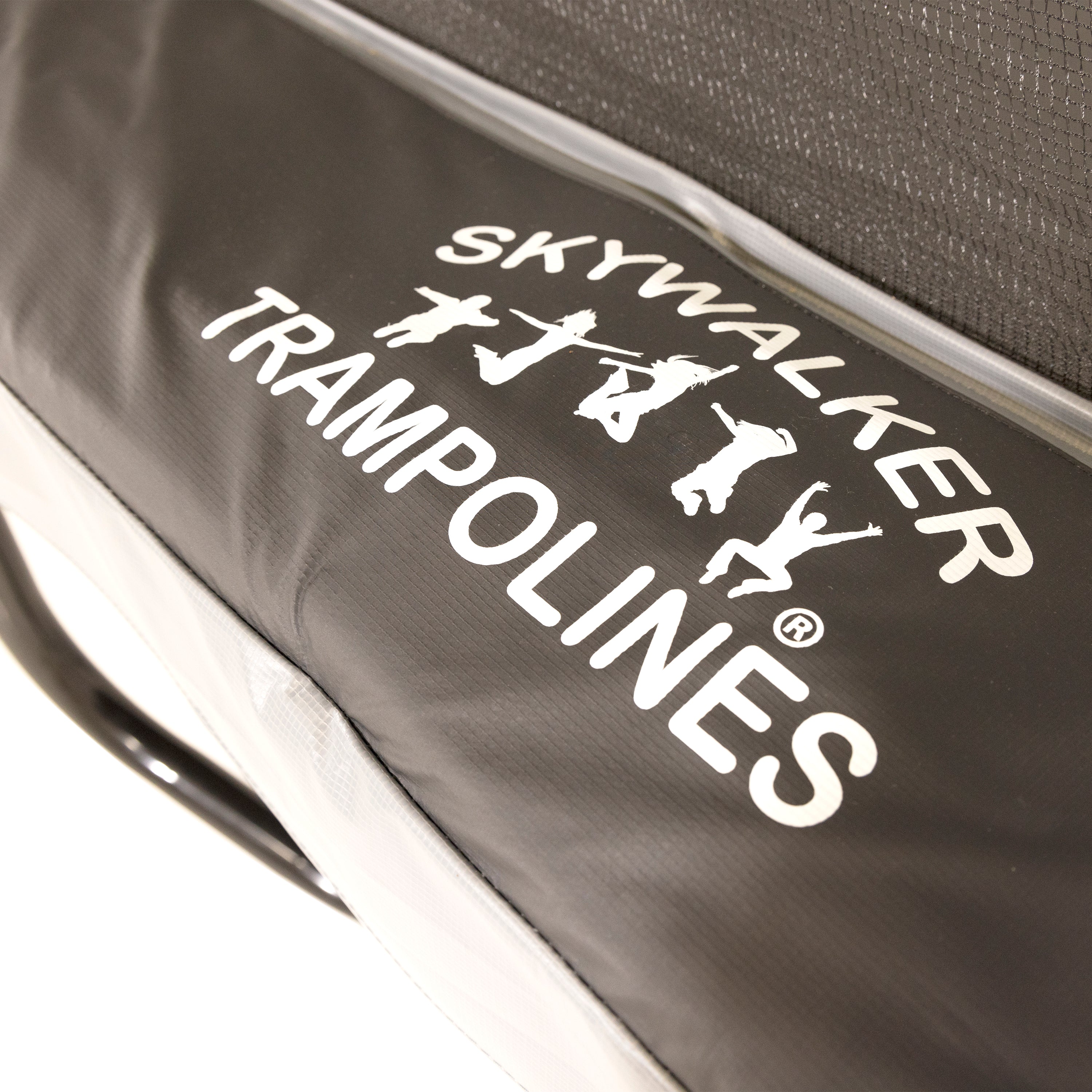Close-up look of a white Skywalker Trampolines logo printed onto a black spring pad. 