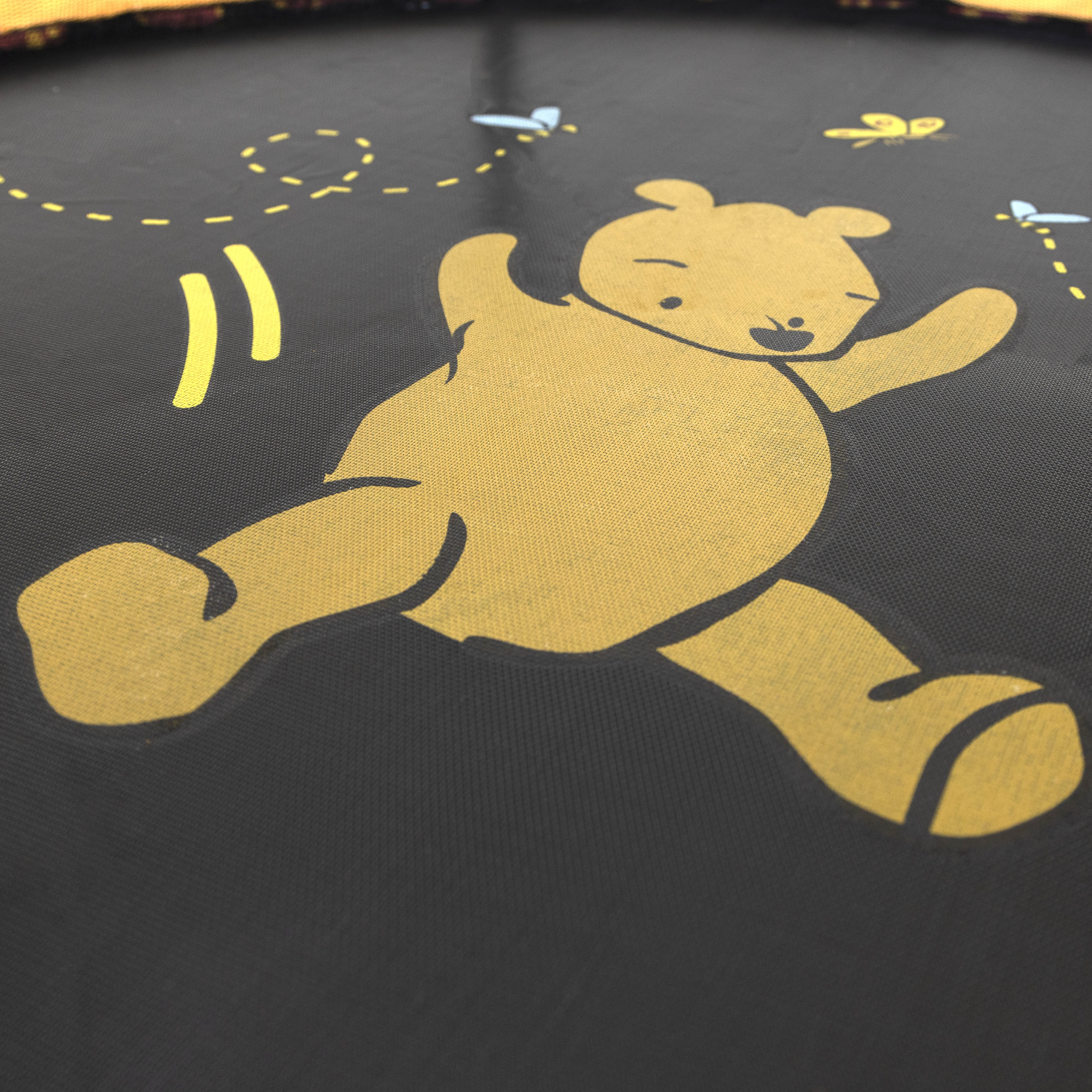 A yellow Winnie the Pooh design is screen printed onto the black jump mat. 