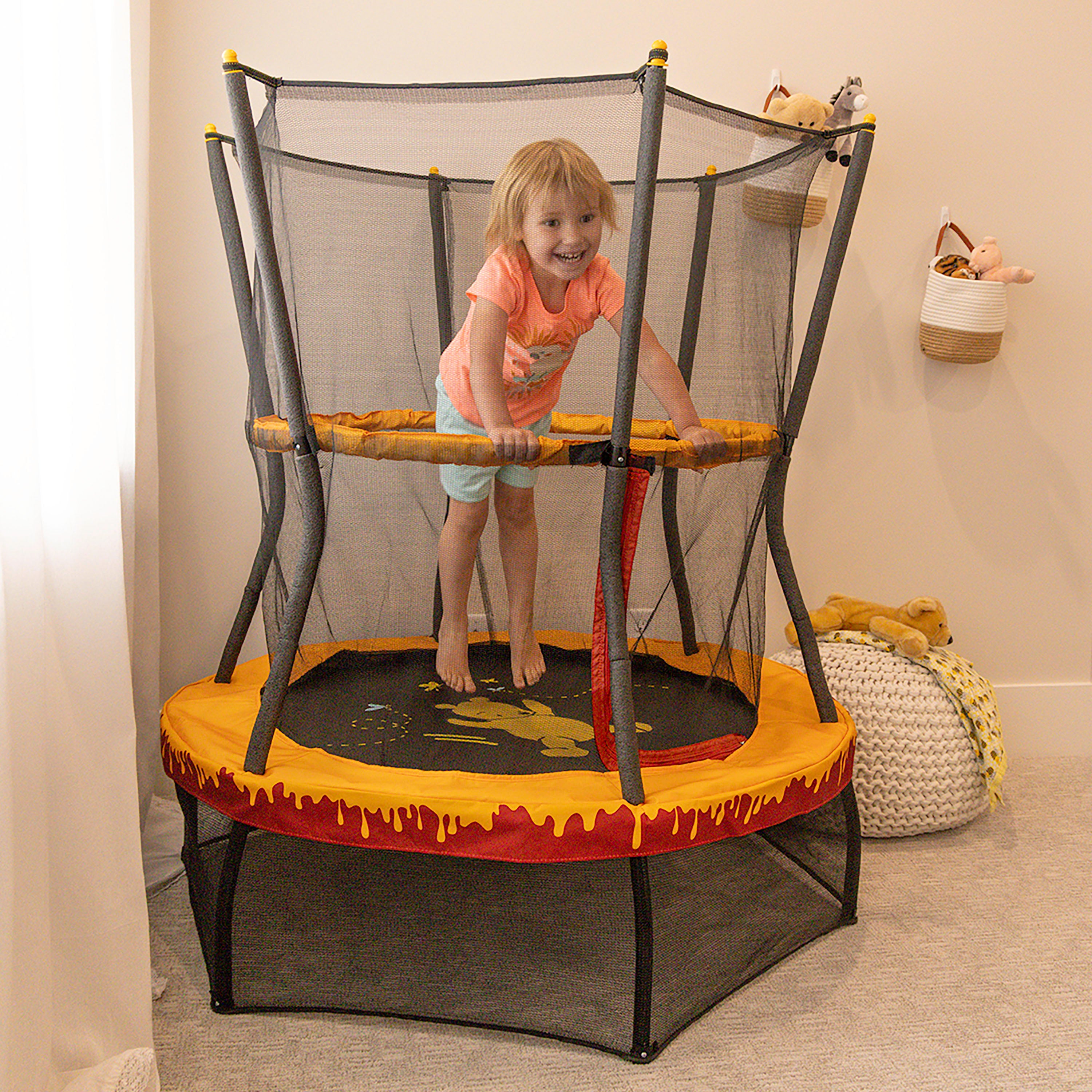 A young girl jumps on the 48” Winnie the Pooh toddler trampoline. 