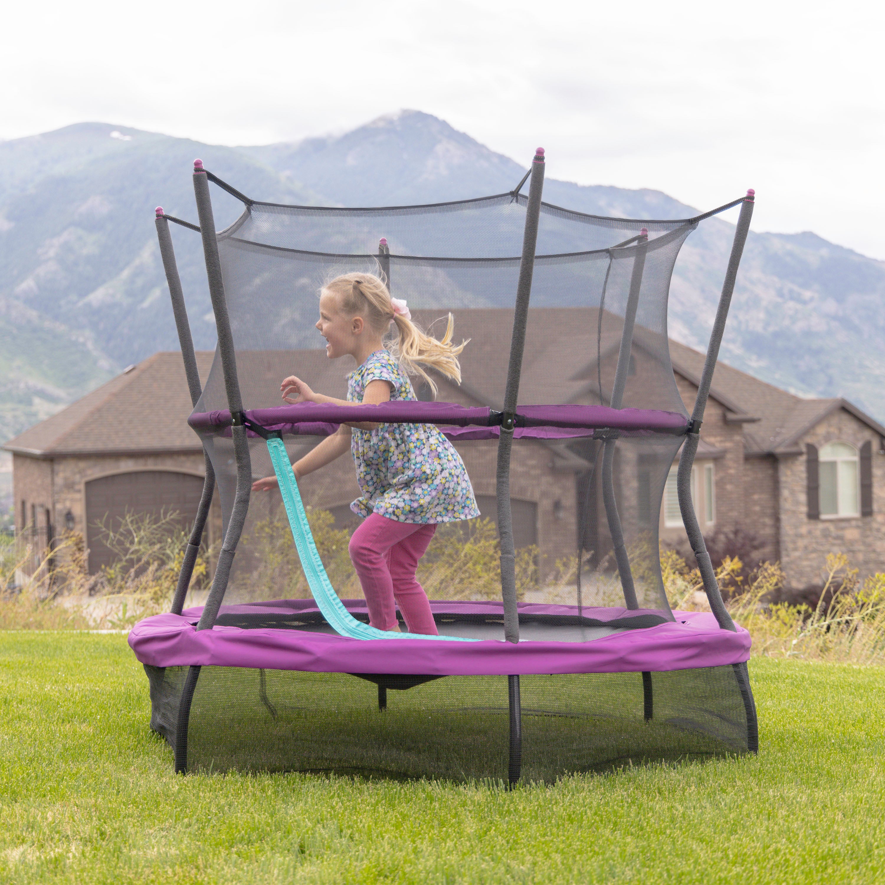 A young girl jumps in the backyard on her 60” Eeyore trampoline. 