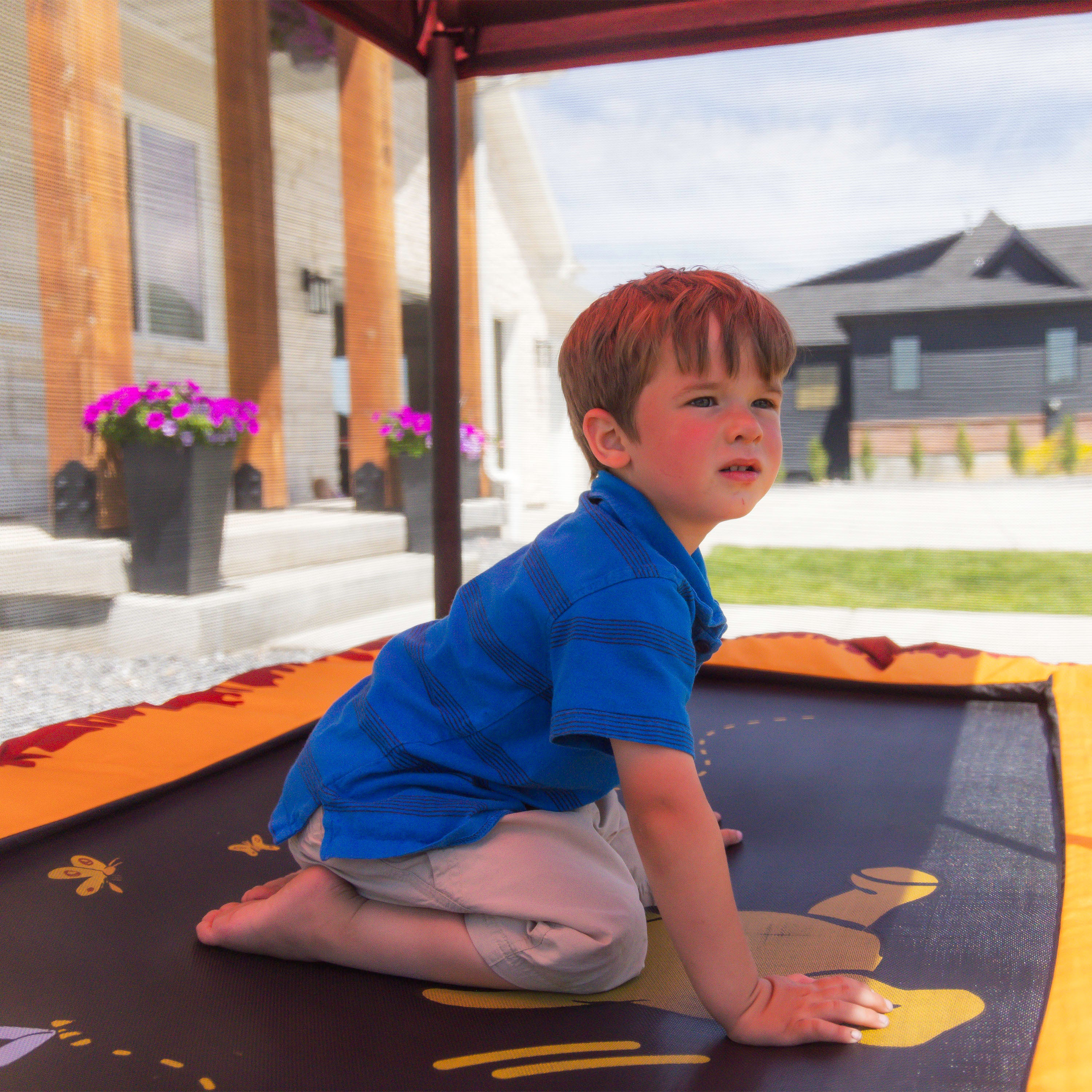 A young boy sits on top of the Winnie the Pooh jump mat design. 