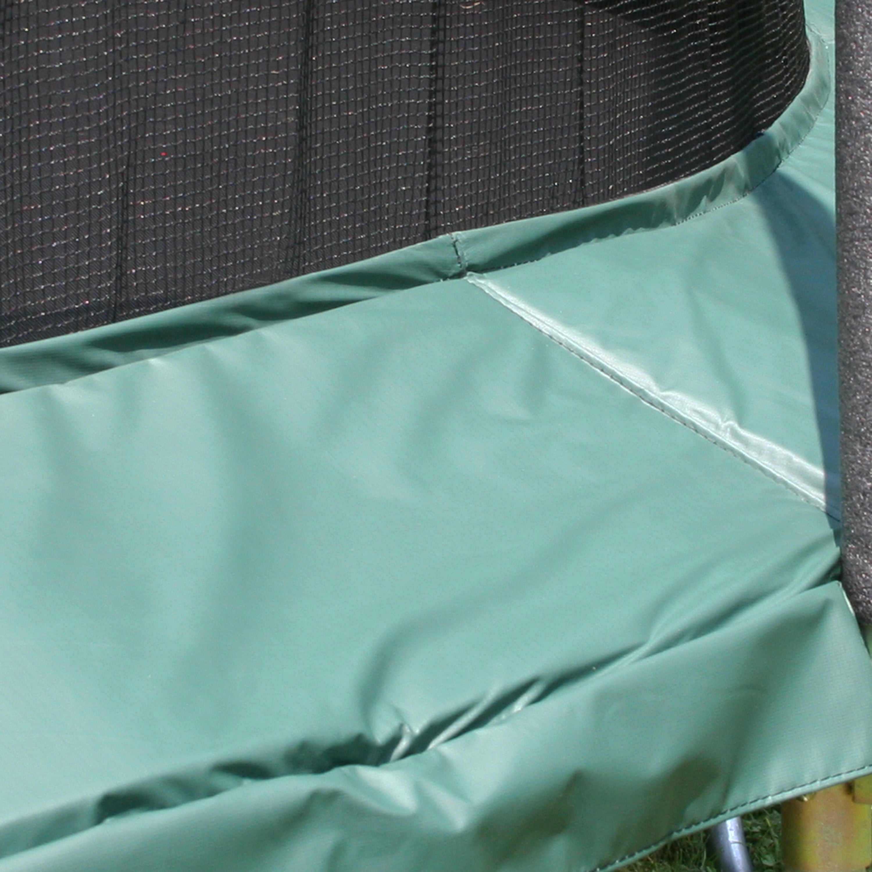 Close-up view of the green spring pad on a trampoline. 
