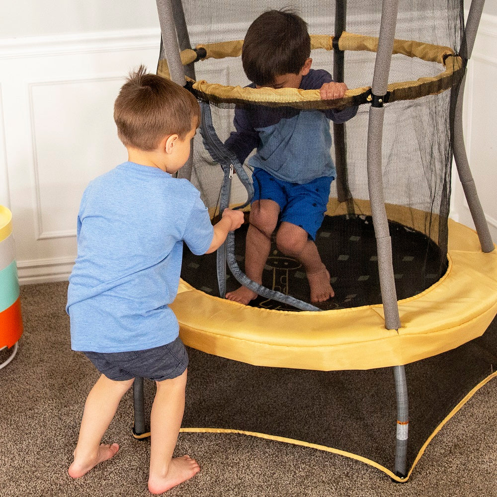 Two young boys try to zip the mini trampoline's enclosure net. 