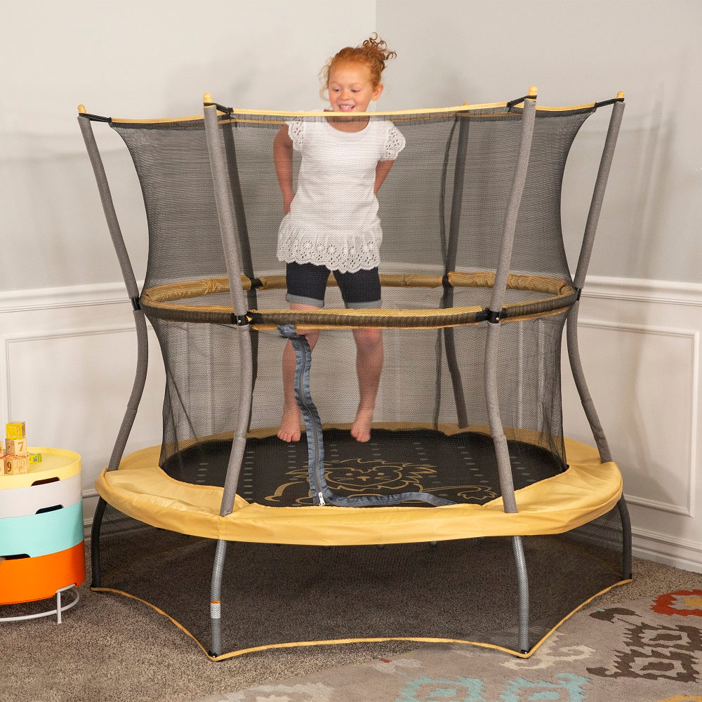 Young girl jumps happily on 60-inch, yellowish-orange, lion-themed mini kids trampoline. 