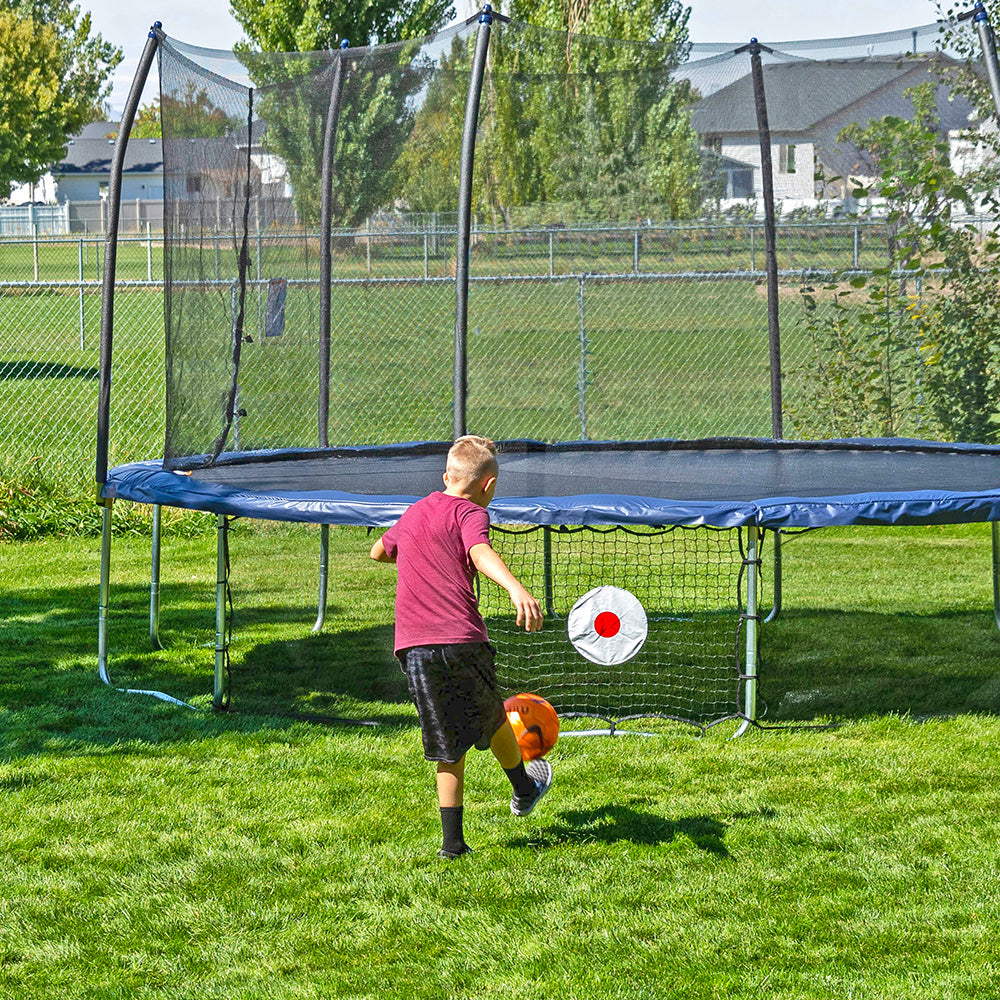 A boy kicks a soccer ball at the Kickback game net target.