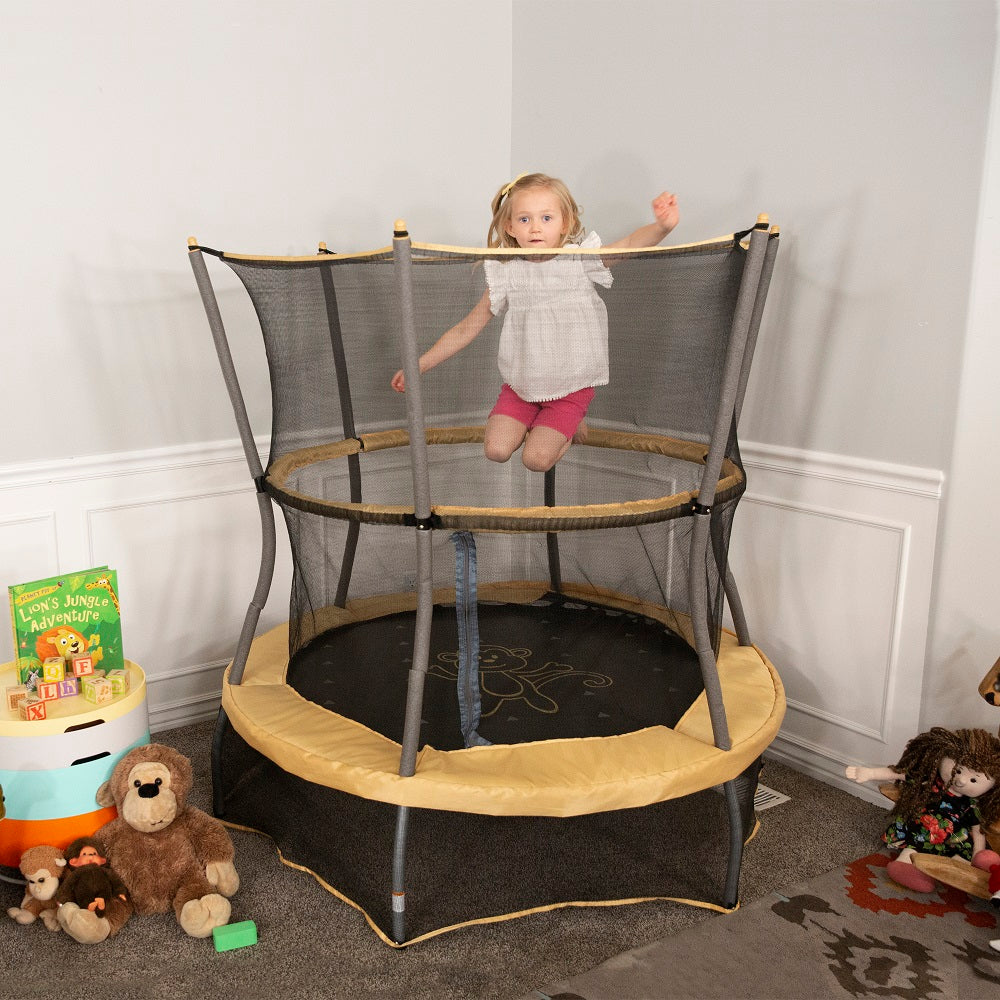 Young girl jumps really high on the yellow and gray 55-inch mini trampoline with monkey design. 