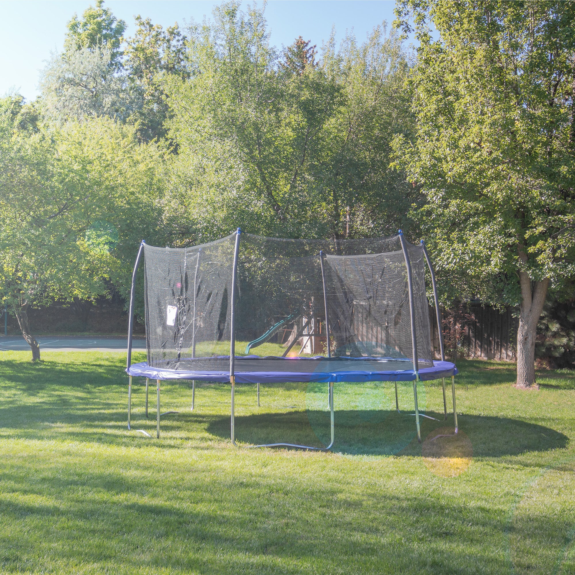  The 16' Round Skywalker Trampoline out in a green backyard. 