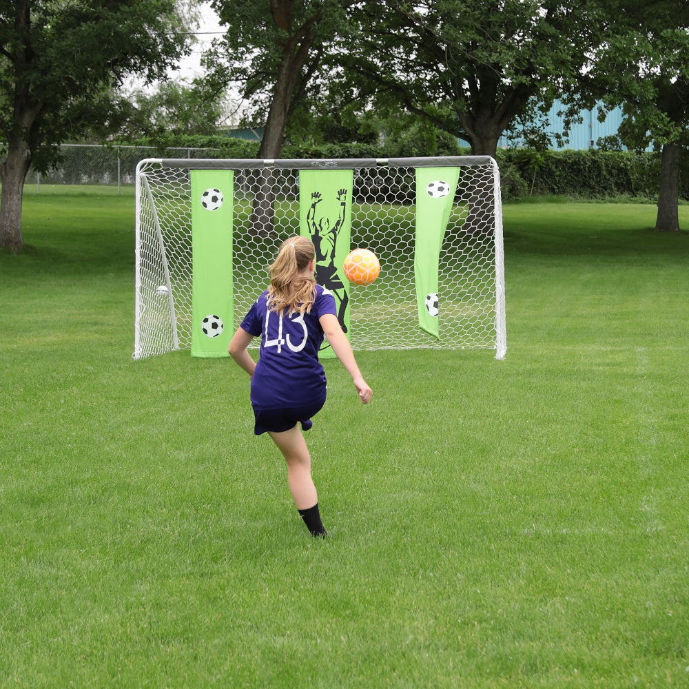 A girl in a purple jersey shoots an orange soccer ball towards the soccer goal. 