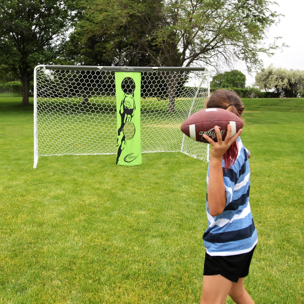 A girl in a striped shirt pulls back to throw a football at the soccer goal's targeting banners. 