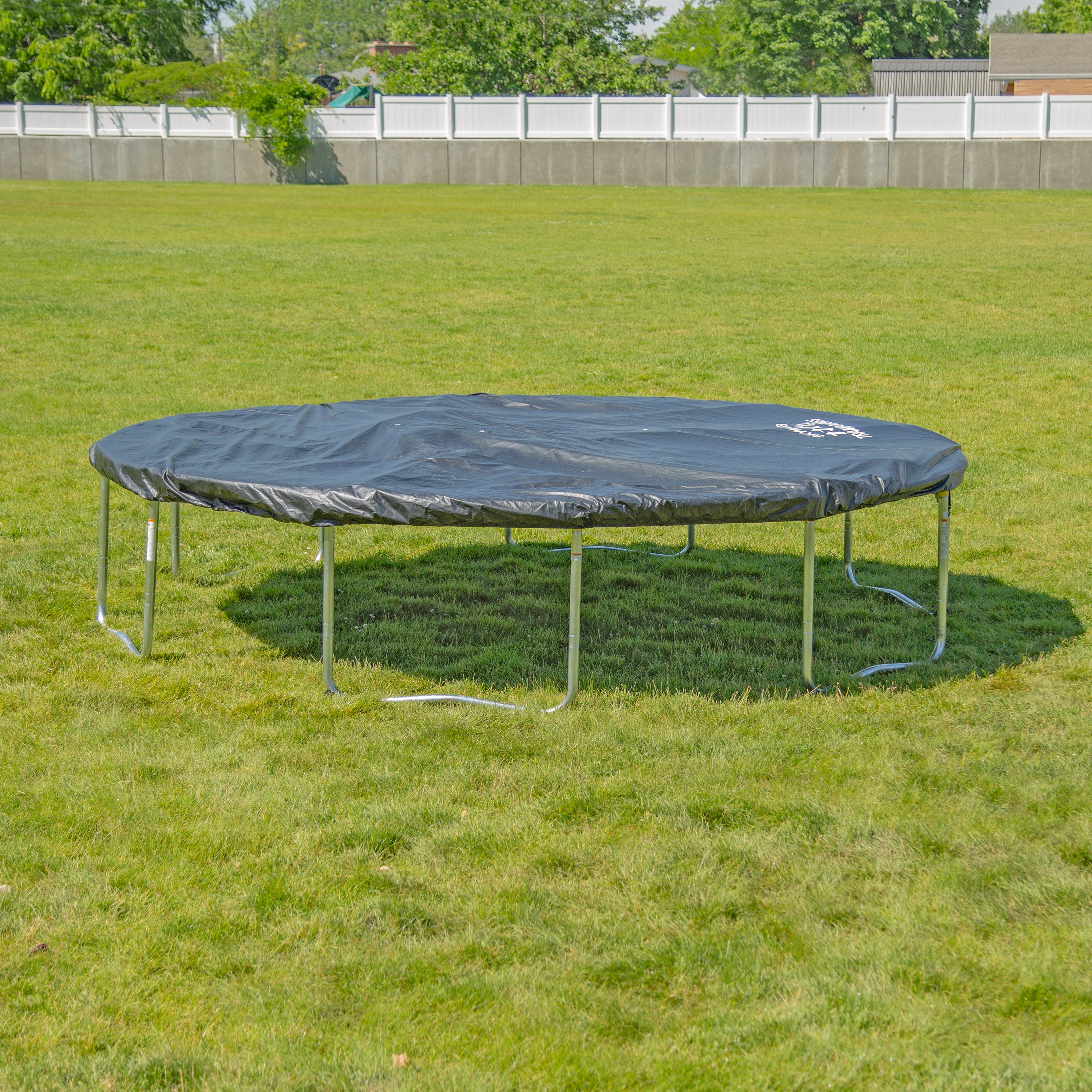17-foot oval trampoline sits in grassy yard covered with the black weather cover. 