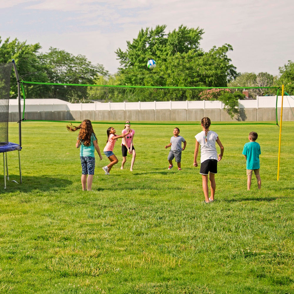 Six young children playing volleyball with the Volleyball Net Accessory. 