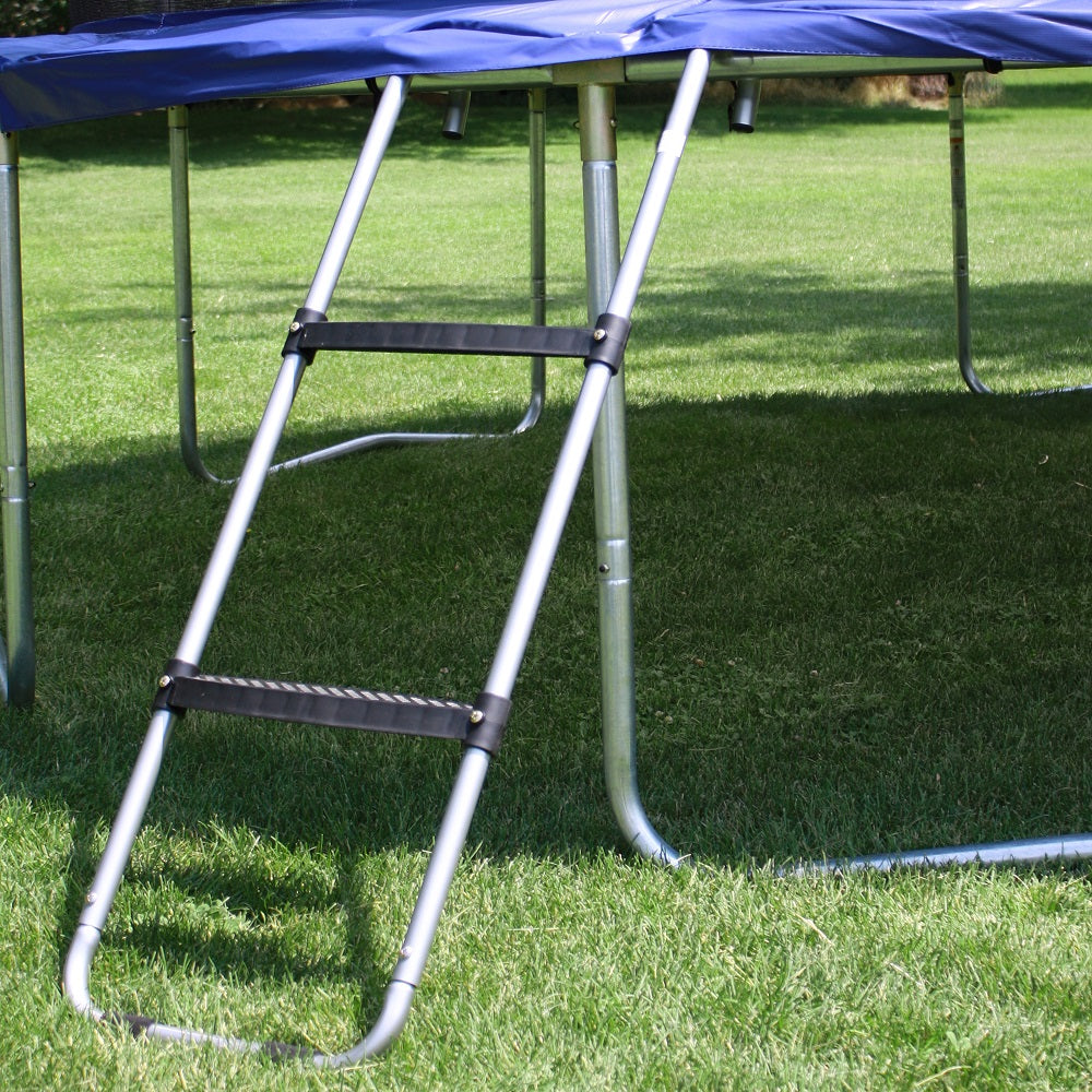 Trampoline with blue spring pad sitting in grass yard with wide-step trampoline ladder attached to frame. 