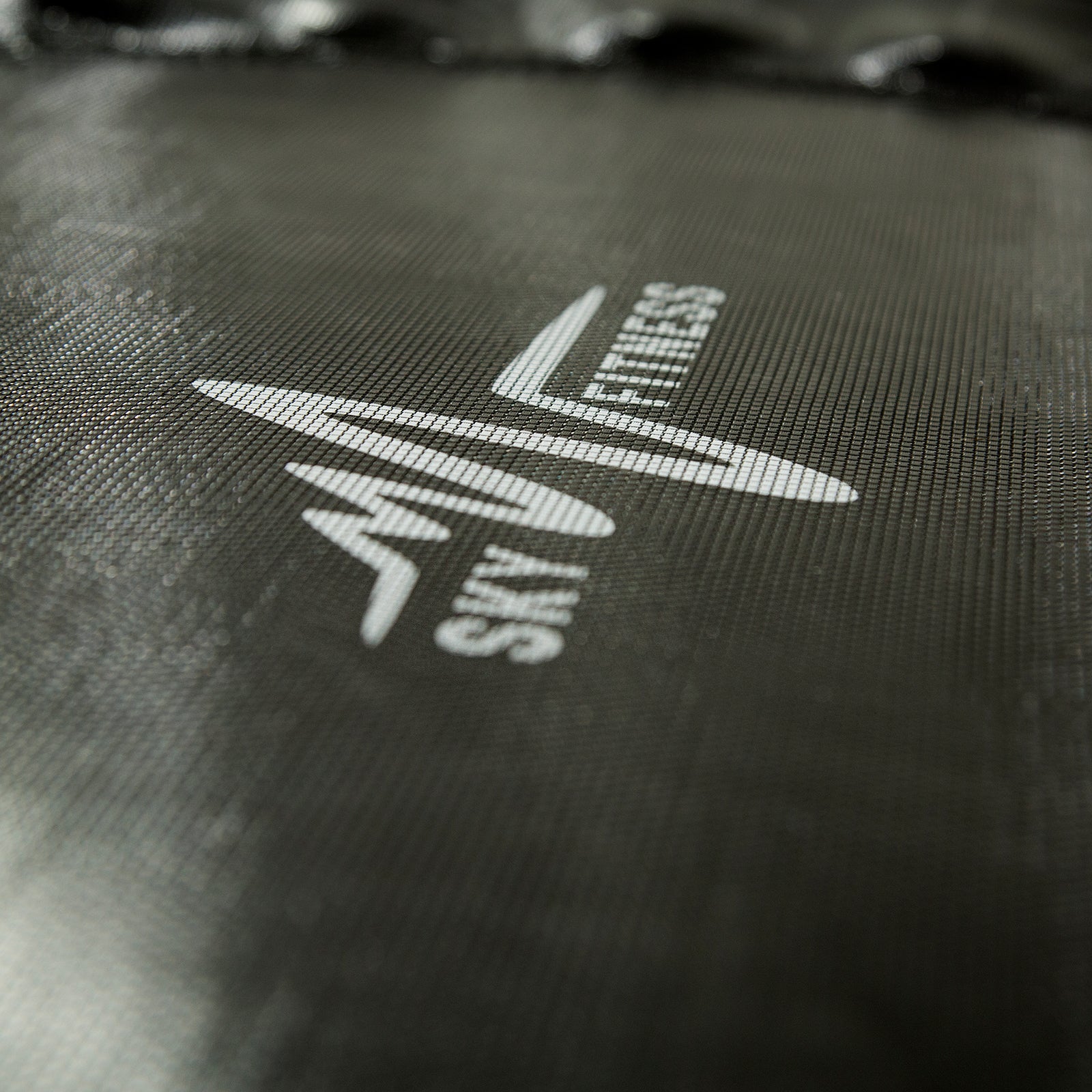 A close-up view of the white SkyFitness logo on the black jump mat. 