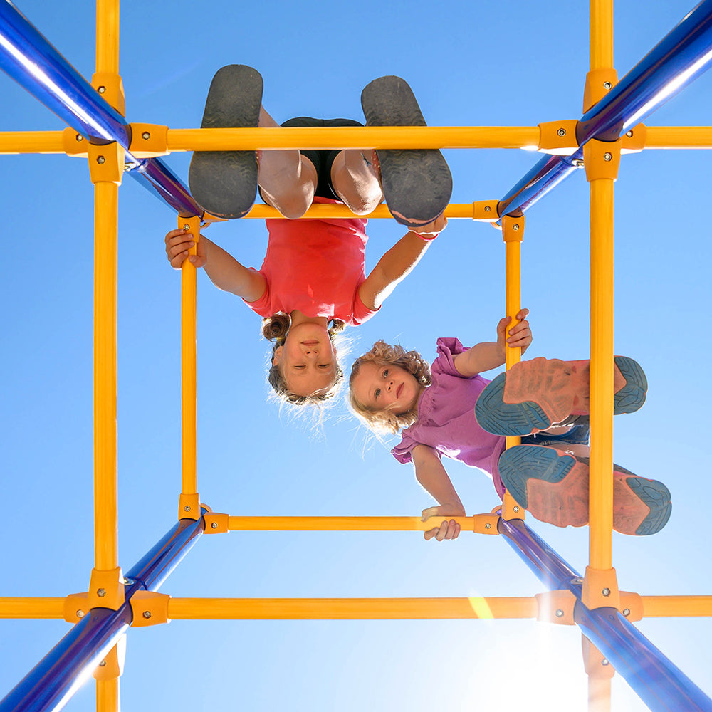 Unique view of the jungle gym looking up from below at the two young girls climbing on the playset. 