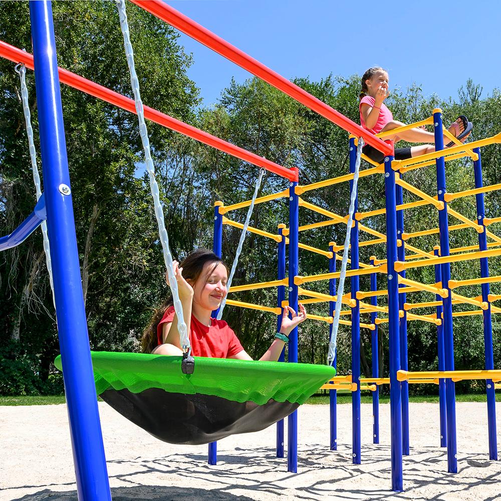 Two girls pretend to meditate while one of them sits in the saucer swing and the other sits above on the jungle gym.