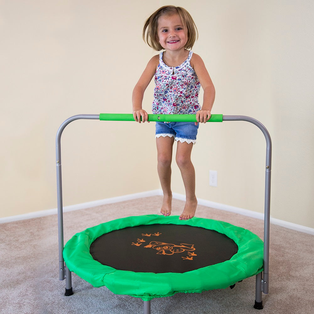Little girl bounces on 36-inch mini kids trampoline while holding onto the green padded handlebar. 