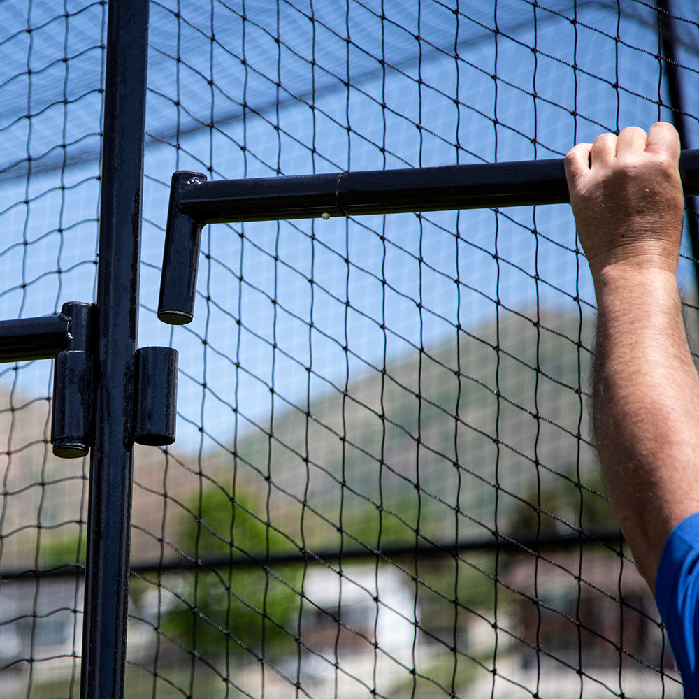 Arms reach up to put the batting cage's frame pieces together. 