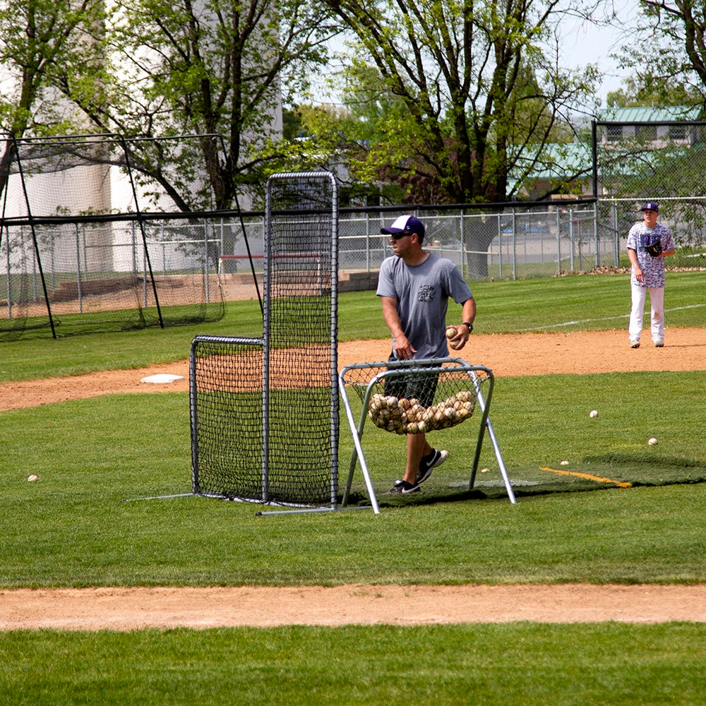 The baseball coach uses the Pitchers L-Screen for protection as he pitches to his players. 