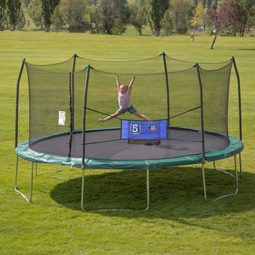 Young girl leaping on a 16-foot oval trampoline with a green spring pad and blue Double-Toss game stretched across the front. 