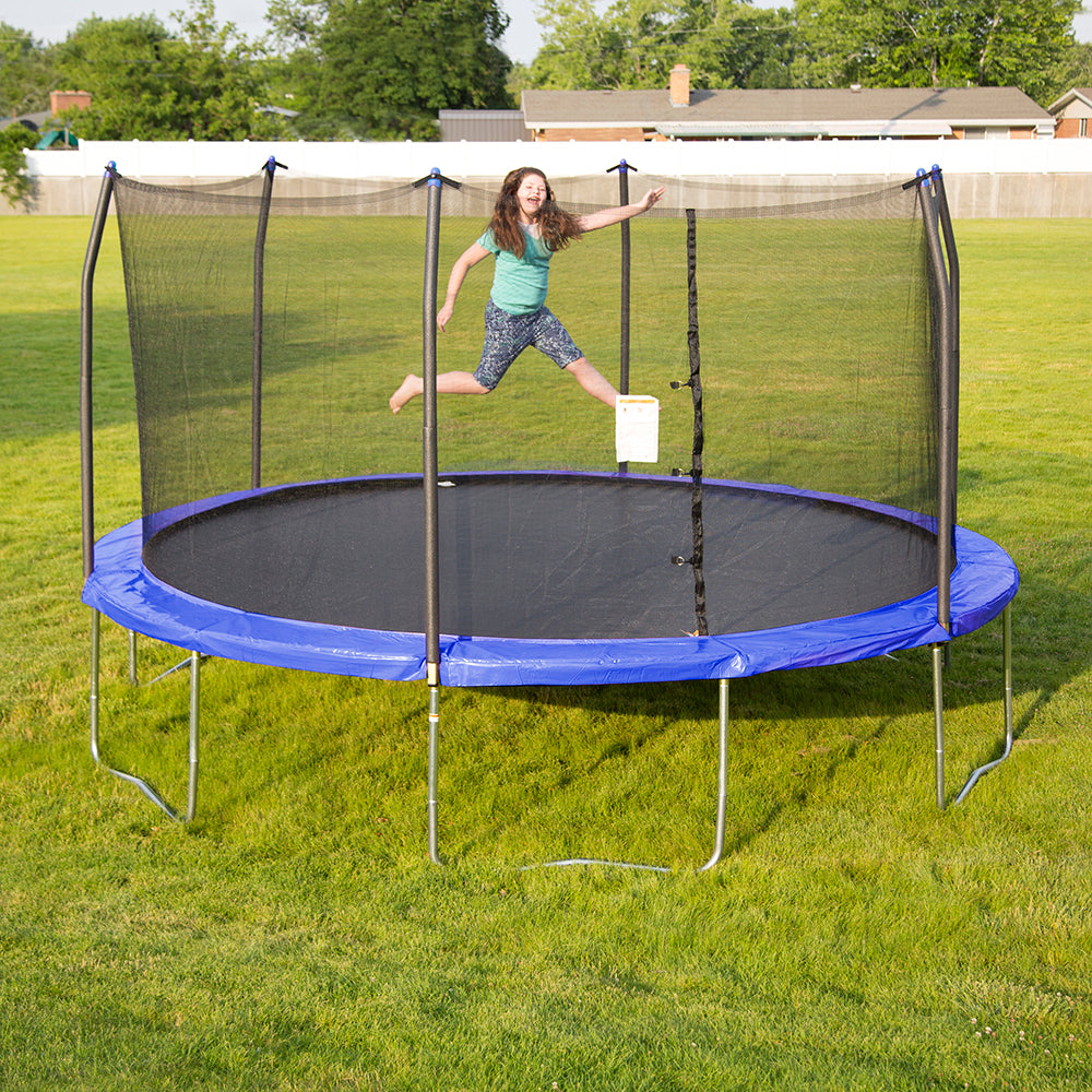 Young girl happily jumping on fifteen-foot round trampoline with blue spring pad and blue pole caps. 