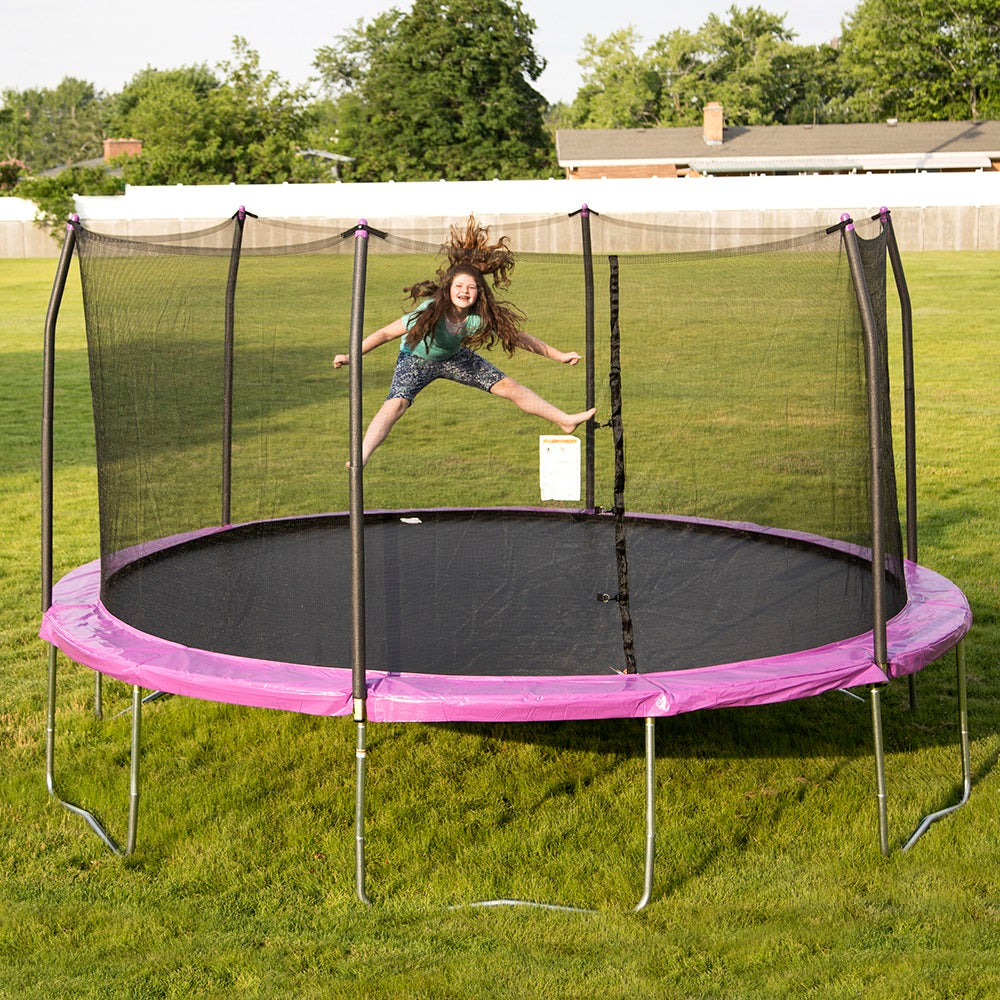 Girl does the splits while jumping on the 15-foot round trampoline with purple spring pad.