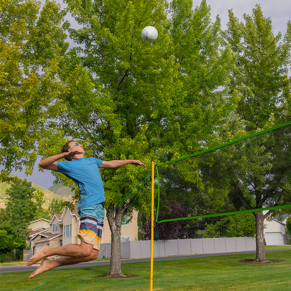 Volleyball player jumping mid-air to spike the volleyball over the net. 